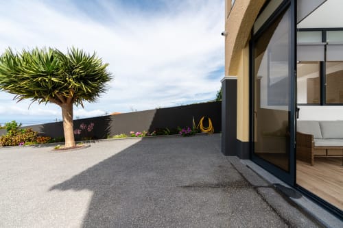 Modern patio at Michaels Garden apartment in Calheta with coastal views, palm tree, and black-framed glass doors