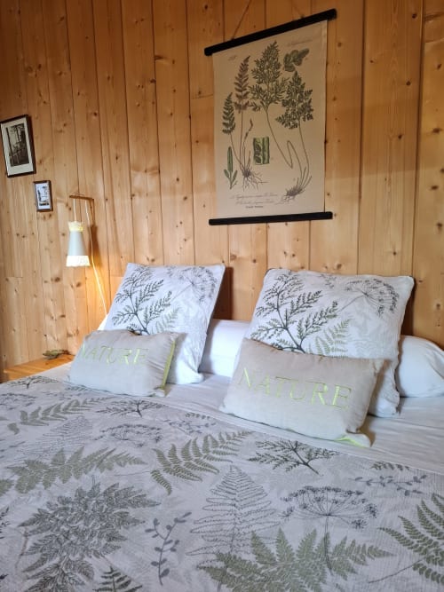 Chambre accueillante aux Gravets B&B avec literie botanique, oreillers à motif fougère, murs en bois et art nature