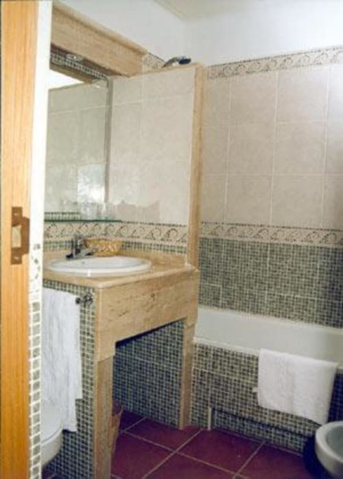 Baño moderno en la Habitación Estándar del Hotel Plaza Chica, Cartaya, con paredes alicatadas, lavamanos redondo, bañera e inodoro