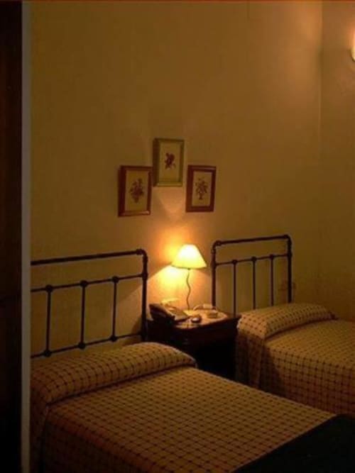 Habitación estándar del Hotel Plaza Chica en Cartaya con dos camas individuales, lámpara de noche y arte decorativo en la pared