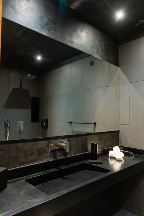 Salle de bain moderne au Domaine de la Peyrine avec plan de travail foncé, vasque, grand miroir et carrelage contemporain à Carignan