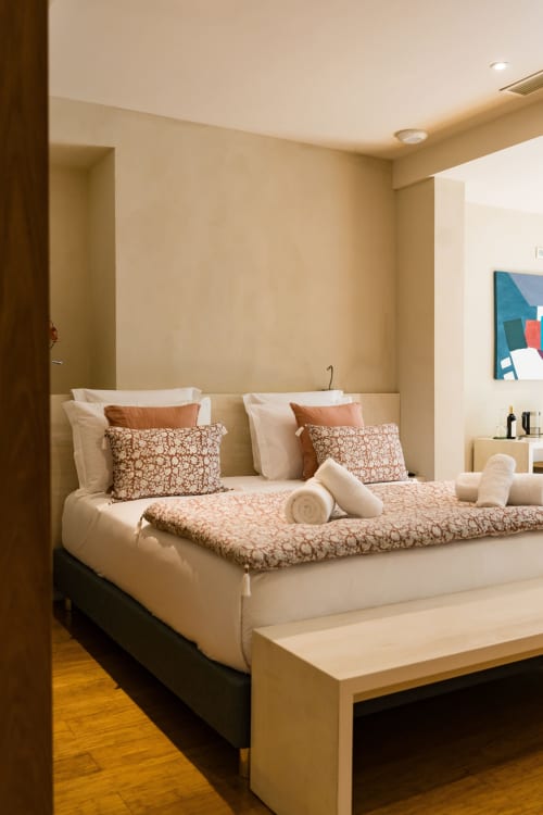 Chambre Chickadee Suite au Domaine de la Peyrine avec literie beige élégante, coussins décoratifs et éclairage chaleureux