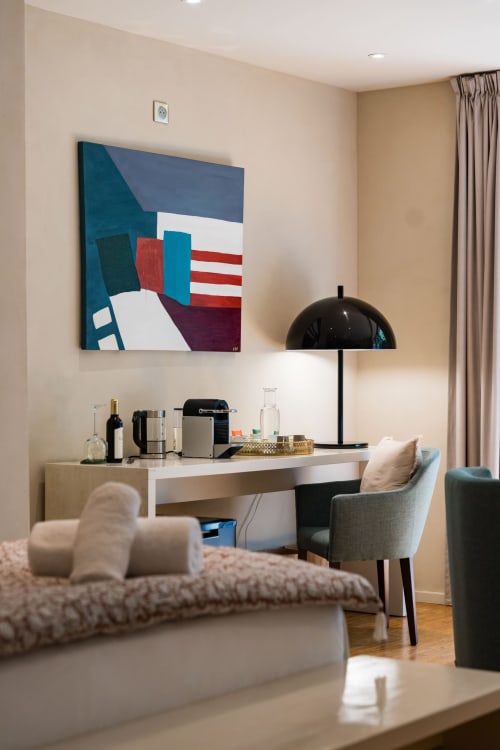 Espace de travail moderne d'une chambre d'hôtel avec œuvre d'art géométrique, lampe dome noire et sièges confortables dans la Suite Chickadee