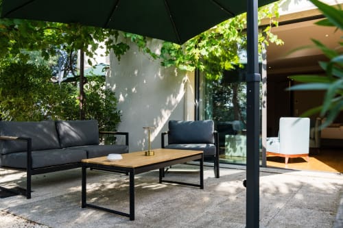 Terrasse de jardin ombragée à la Domaine de la Peyrine avec mobilier noir, table en bois et verdure luxuriante