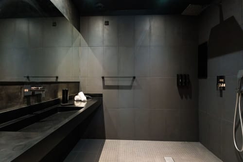 Salle de bain luxe moderne à l'hôtel Domaine de la Peyrine avec carrelage foncé, vasque, douche italienne et équipements contemporains