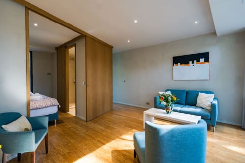 Espace séjour de la Suite Robin au Domaine de la Peyrine avec assises bleues, parquet et vue sur le jardin