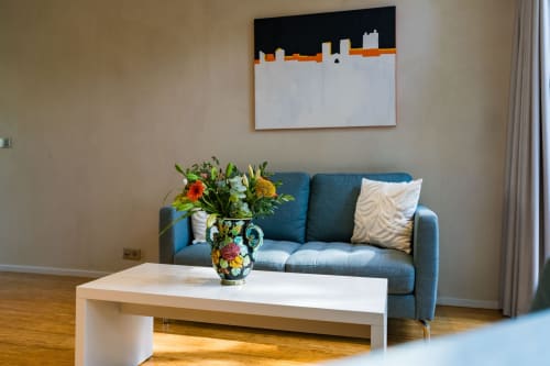 Séjour moderne de la Suite Robin au Domaine de la Peyrine avec canapé bleu, table blanche, fleurs colorées et panorama urbain
