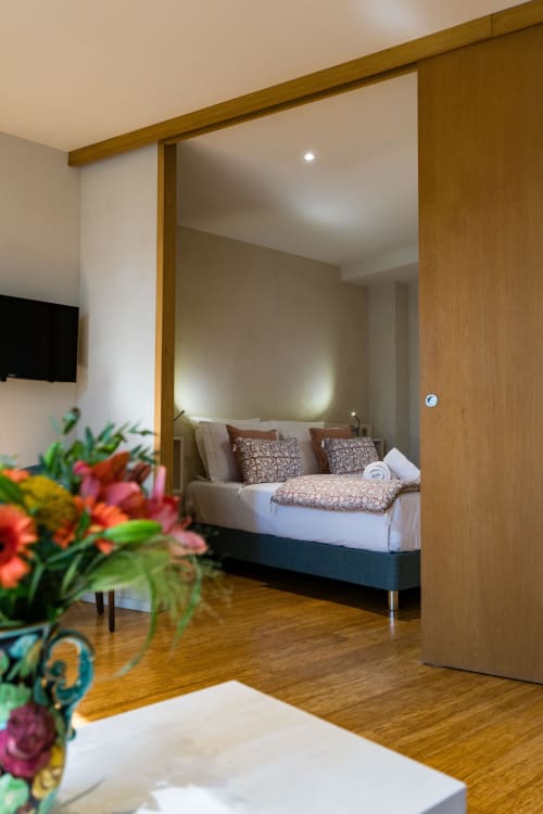 Chambre Robin Suite au Domaine de la Peyrine avec lit à cadre bois, fleurs colorées et équipements modernes à Carignan de