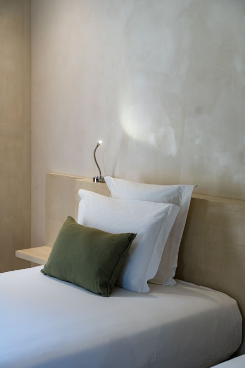 Chambre moderne au Domaine de la Peyrine avec oreillers blancs, coussin vert et tête de lit minimaliste beige