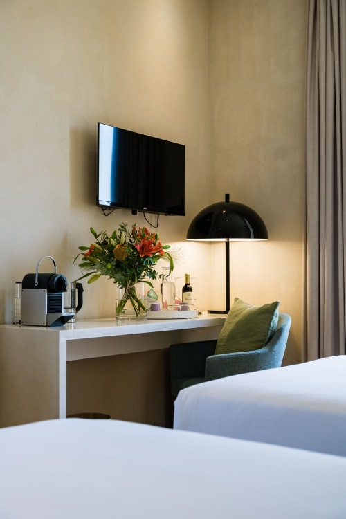 Espace de travail moderne à l'hôtel Domaine de la Peyrine avec bureau, télévision écran plat, fleurs fraîches et fauteuil confortable