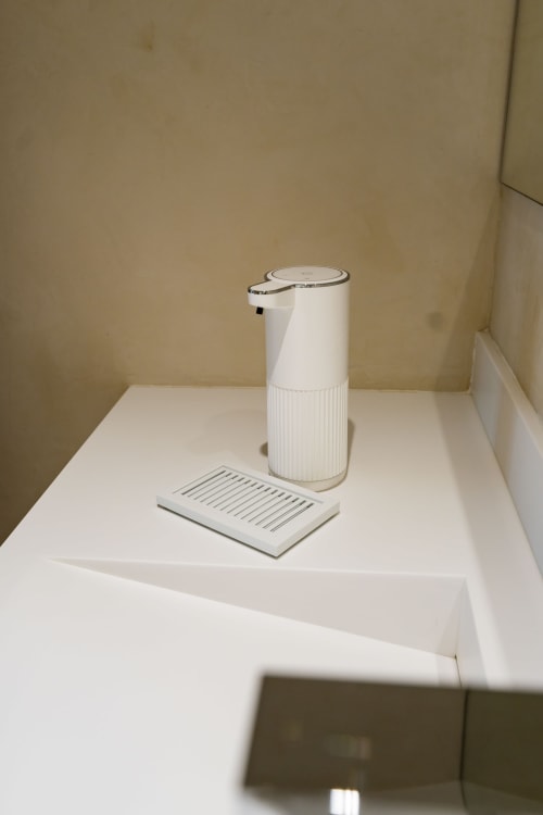 Distributeur de savon blanc automatique et plateau sur le lavabo de la salle de bains de l'hôtel Domaine de la Peyrine à Carignan de Bordeaux