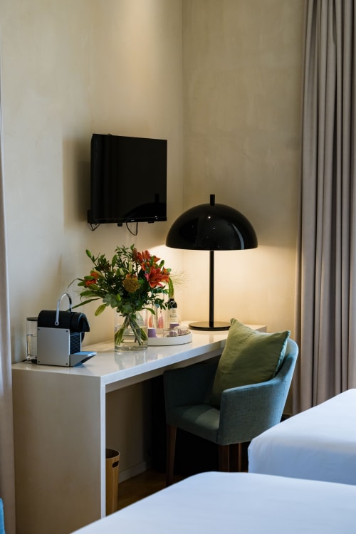 Espace de travail moderne à Domaine de la Peyrine : bureau, chaise, lampe dôme noire, fleurs fraîches et TV murale