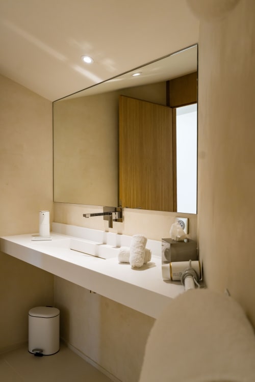 Salle de bain moderne du Domaine de la Peyrine avec plan de travail blanc, grand miroir et accents en bois
