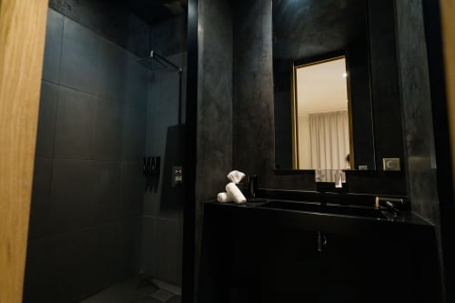 Salle de bains moderne noire de la Suite Hirondelle au Domaine de la Peyrine, avec vasque, miroir et douche
