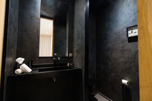 Salle de bains élégante noire dans la Suite Hirondelle du Domaine de la Peyrine avec carrelage foncé, vasque et miroir