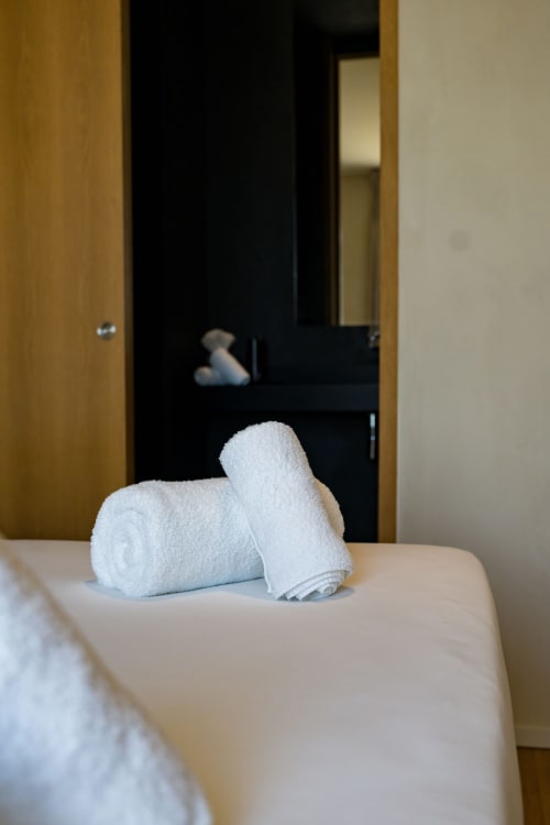Serviettes blanches roulées exposées sur le lit de la Suite Hirondelle au Domaine de la Peyrine, Carignan de Bordeaux