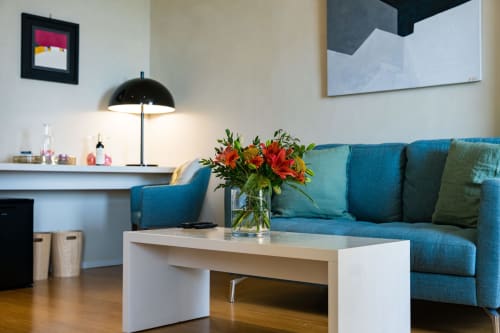 Suite d'hôtel moderne avec canapé bleu, table basse blanche et fleurs rouges au Domaine de la Peyrine à Bordeaux