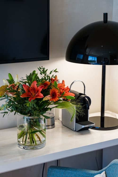 Bureau moderne de la Suite Pinson à Domaine de la Peyrine avec fleurs rouges, lampe dôme noire et espace de travail donnant sur le jardin