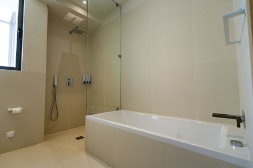 Salle de bains moderne du Domaine de la Peyrine avec douche à l'italienne, baignoire blanche et carrelage crème
