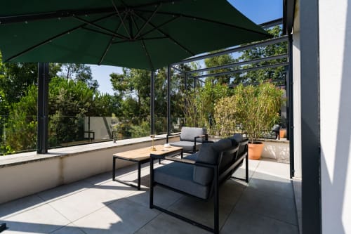 Terrasse de la Suite Pinson au Domaine de la Peyrine avec salon de détente, parasol vert et vue sur le jardin