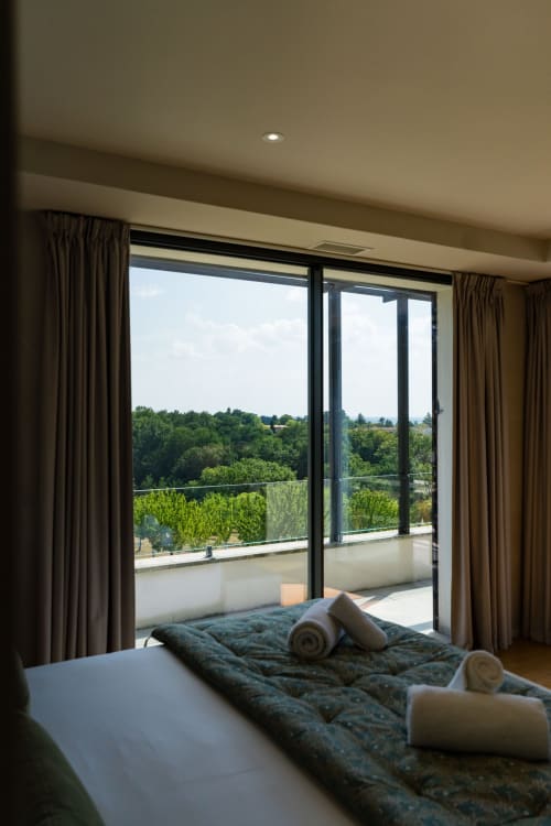 Chambre de la Suite Pinson avec balcon donnant sur les jardins verdoyants du Domaine de la Peyrine, Bordeaux