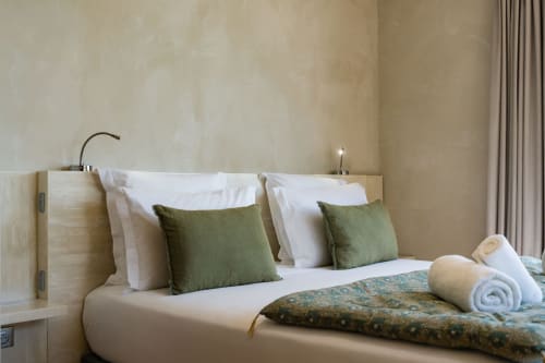 Suite Pinson du Domaine de la Peyrine avec lit en bois clair, linge blanc, coussins verts et murs neutres