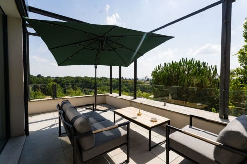 Terrasse ombragée du Domaine de la Peyrine avec parasol vert, chaises longues et vue sur le jardin à Carignan de Bordeaux