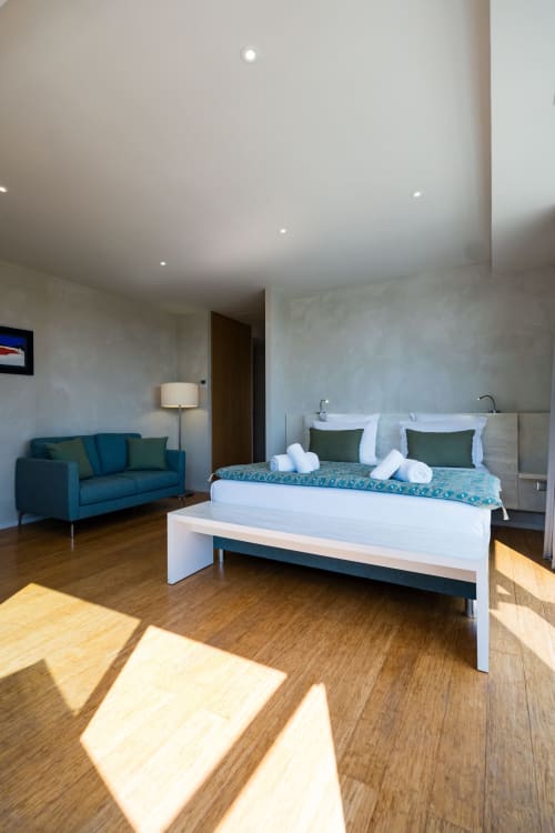 Suite Pinson du Domaine de la Peyrine : lit queen-size, canapé bleu canard, parquet et décoration moderne à Carignan de Bordeaux