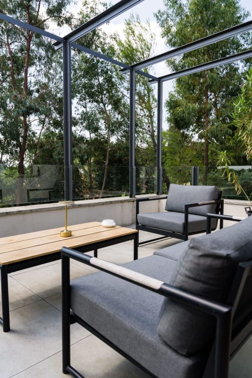 Balcon moderne aux parois vitrées du Domaine de la Peyrine, mobilier gris, table en bois et vue sur le jardin