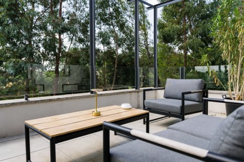 Terrasse moderne du Domaine de la Peyrine avec mobilier gris, table en bois et vue sur le jardin