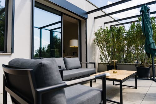 Salon de patio moderne au Domaine de la Peyrine avec mobilier gris, table en bois et vue sur le jardin à Carignan de