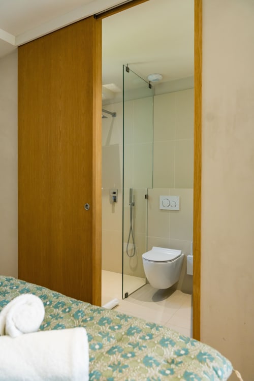 Salle de bains contemporaine de la suite Domaine de la Peyrine avec douche à l'italienne, toilettes murales et porte coulissante en bois