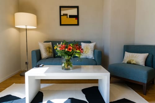 Élégant coin salon dans la Suite Tourterelle du Domaine de la Peyrine avec canapés bleu-vert, table blanche et fleurs fraîches