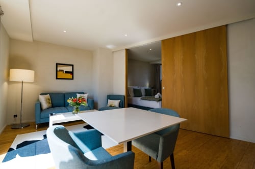Suite Tourterelle au Domaine de la Peyrine avec coin salon bleu, table à manger blanche et vue sur la chambre à Carignan de Bordeaux.