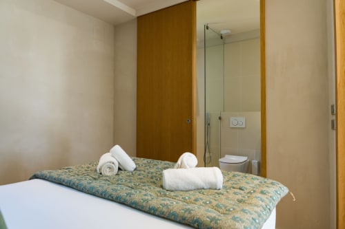 Chambre Tourterelle au Domaine de la Peyrine avec serviettes blanches sur lit à motifs et salle de bain attenante avec douche