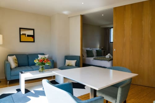 Suite Tourterelle du Domaine de la Peyrine avec canapé turquoise, bureau blanc et vue ouverte sur la chambre à Bordeaux