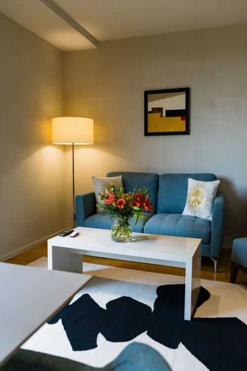 Salon moderne de la Suite Tourterelle au Domaine de la Peyrine avec canapé bleu, table basse blanche et fleurs fraîches