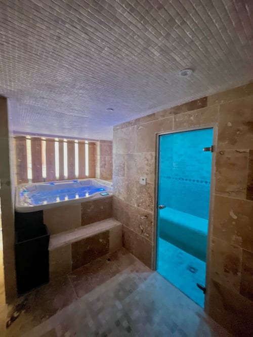 Luxueuse spa room du Domaine Les Racines avec bain à remous, douche hammam et éclairage tamisé à Croix-Moligneaux