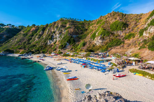 Barche da pesca colorate sulla spiaggia incontaminata vicino agli Appartamenti Mottola, Tropea Italia con mare turchese e scogliere spettacolari