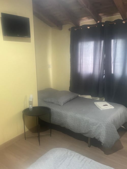 Habitación de hotel en O Esqueiro en Malpica con cama, escritorio, TV, cortinas negras y paredes amarillas
