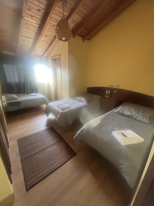 Habitación Sisargas en el Hotel O Esqueiro con camas gemelas, techo con vigas de madera y vistas a la montaña en Malpica