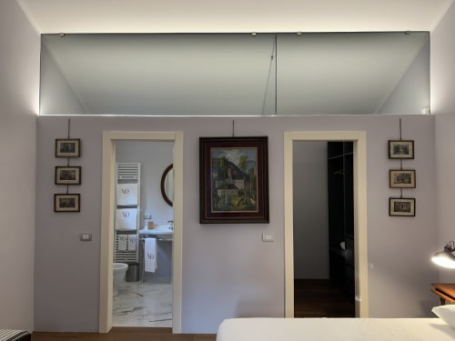 Camera da letto dell'Hotel Villa Dom a Piacenza con bagno, armadio, quadri incorniciati e comfort moderni