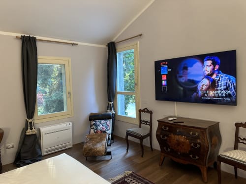 Camera da letto dell'Hotel Villa Dom Piacenza con TV a schermo piatto, mobili in legno, finestre con vista sul giardino e servizi moderni