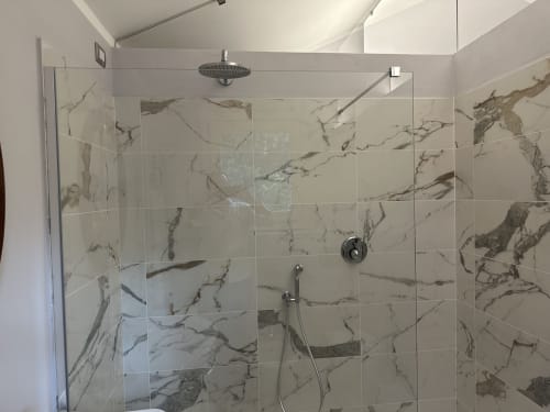 Elegante doccia in marmo con box in vetro alla Villa Dom di Piacenza, dotata di soffione pioggia e doccetta manuale