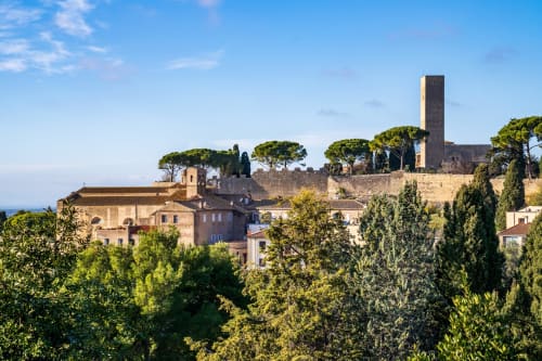 Antico borgo medievale su collina con torre in pietra, chiesa e cipressi vicino Roma