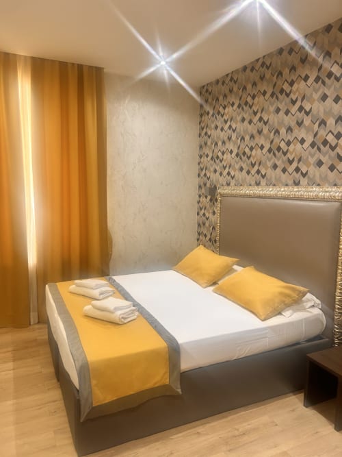 Camera dell'Hotel Ercoli House Roma con letto, accenti gialli, carta da parati geometrica e illuminazione moderna