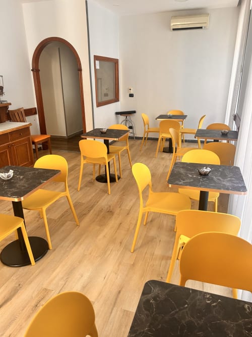 Luminosa sala colazione dell'Hotel Ercoli House Roma con sedie gialle e tavoli in marmo scuro su pavimento in legno