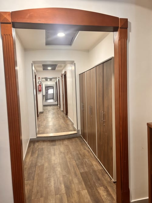Moderno corridoio con pavimentazione in legno all'Hotel Ercoli House B&B di Roma, con porte in legno e luci al soffitto luminose