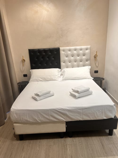 Camera moderna dell'Hotel Ercoli House Roma con testata divisa e biancheria bianca fresca
