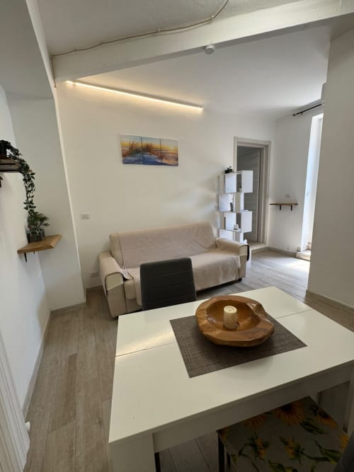 Appartamento Victoria al Queen Hotel, Campofilone: salotto moderno con divano beige, tavolo bianco, dettagli in legno e luce naturale